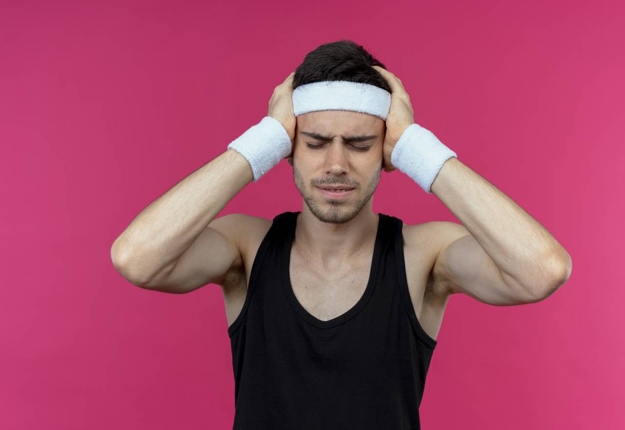 Young Sporty Man Headband Looking Unwell Holding His Head With Hands Suffering From Strong Headache Standing Pink Background